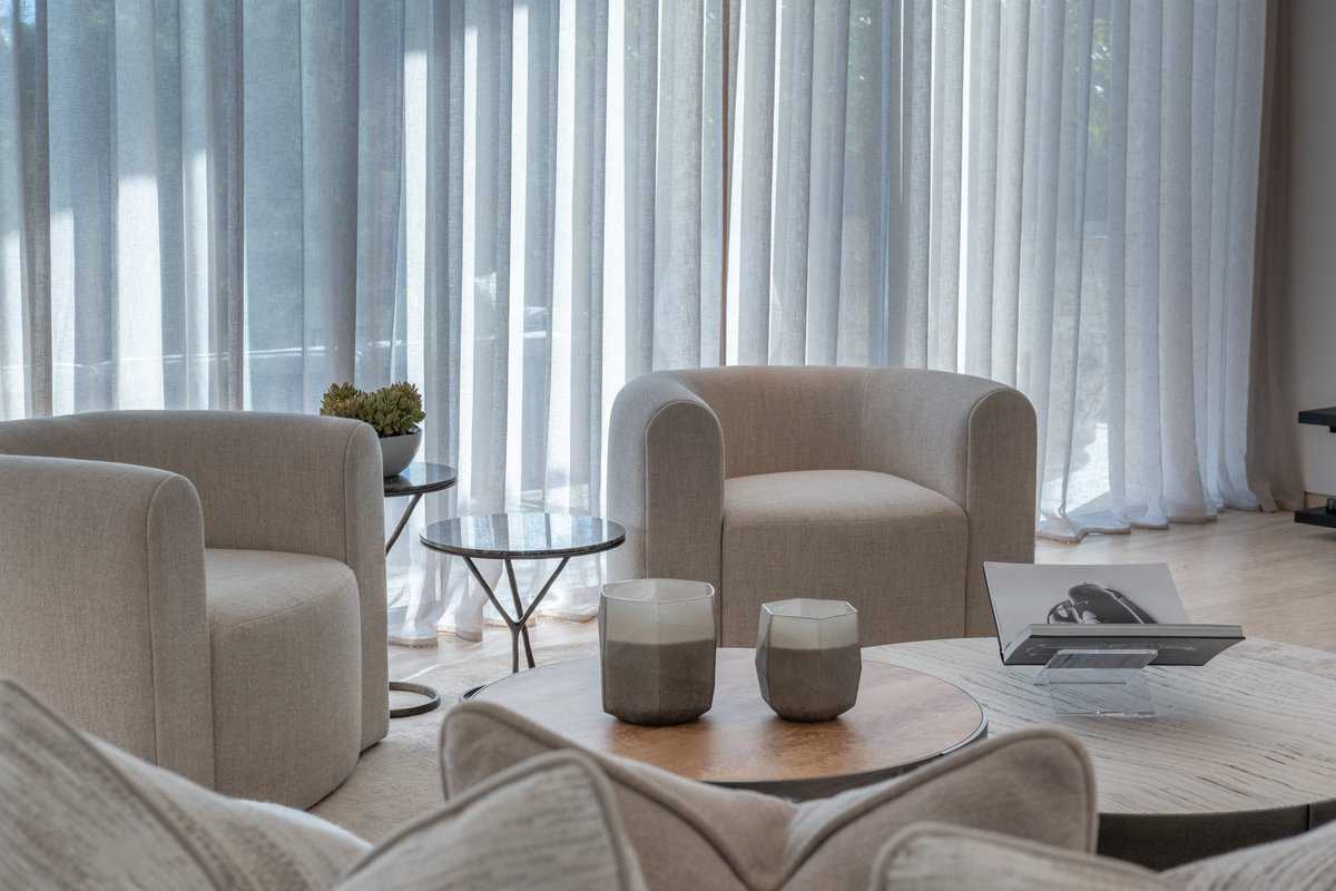 Curved lounge chairs beside full-height curtains